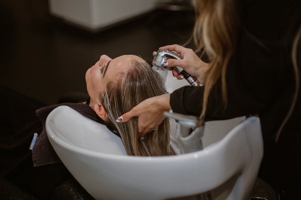 A stylist washes a client's hair to begin her treatment at our hair salon near Richmond.