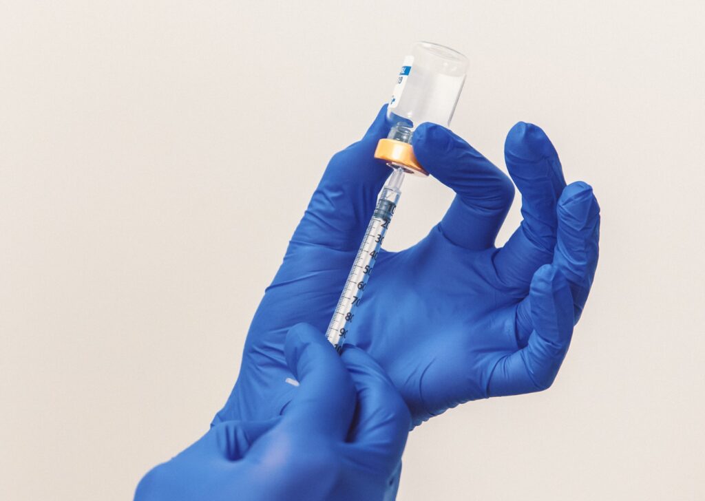 A provider wearing blue gloves prepares a syringe with peptides at our peptide clinic in Winchester, Indiana, for treatment.