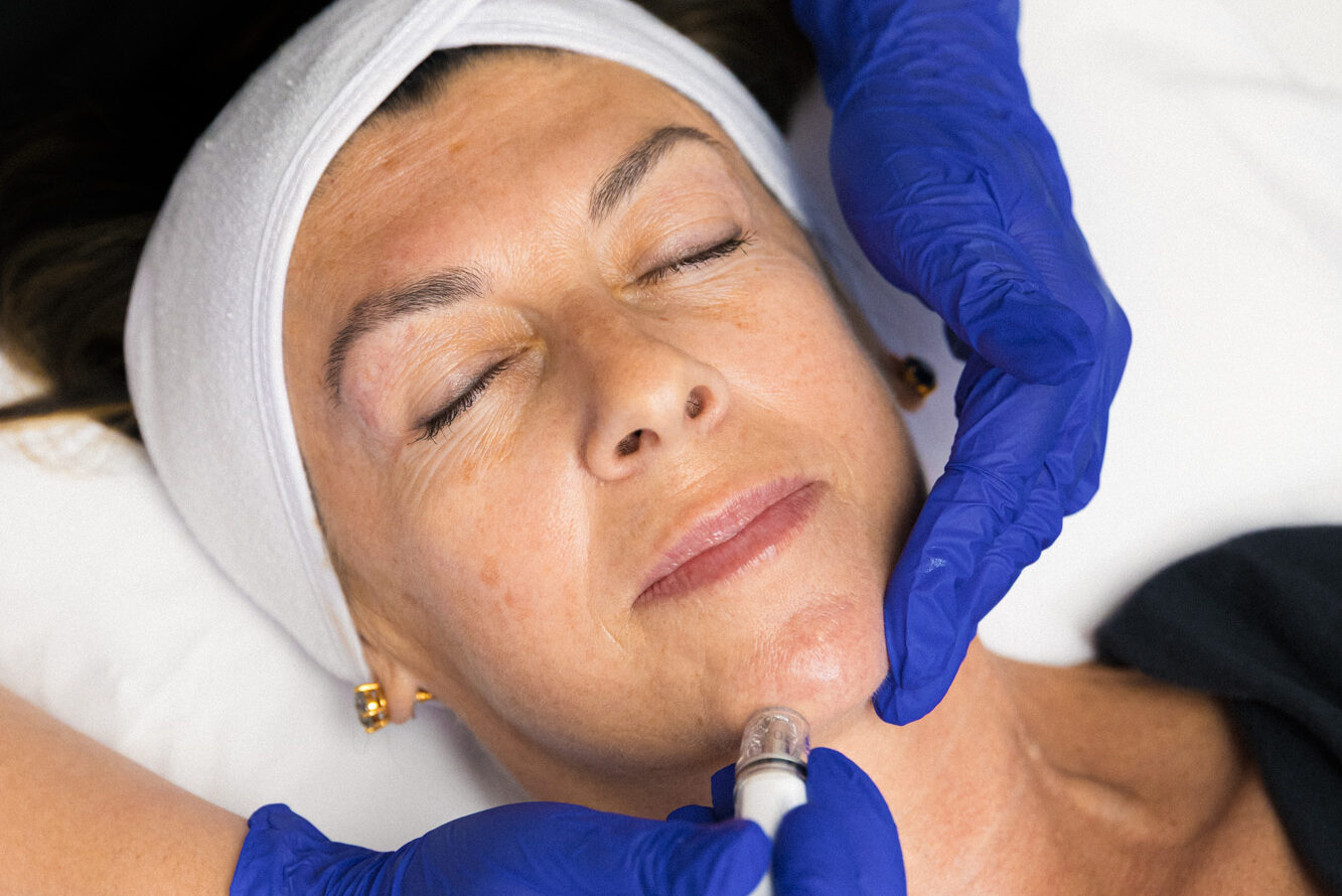 An aesthetician uses the DiamondGlow handpiece during a patient's facial. Facials are popular aesthetic add-ons for clients coming from our hair salon near Richmond.